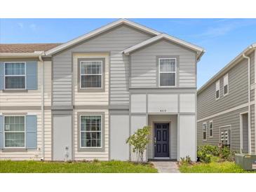 Charming two-story townhome featuring gray siding, well-manicured lawn, and inviting entryway at 4310 Lana Ave, Davenport, FL 33897
