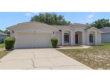 Charming single-story home featuring a two-car garage, manicured lawn, and a welcoming red front door at 160 Conch Dr, Kissimmee, FL 34759
