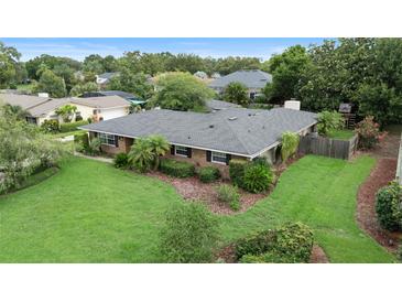 An aerial view of a brick house with a well-manicured lawn, mature trees, and an expansive roof at 1271 Old Mill Rd, Orlando, FL 32806