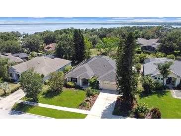 A well-maintained home featuring a lush lawn and mature landscaping, nestled near a tranquil lake at 13631 Via Roma Cir, Clermont, FL 34711