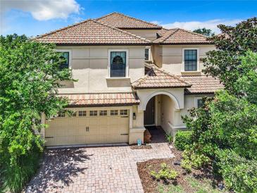 Charming two-story home featuring a red tile roof, a brick driveway and an attached two-car garage at 1478 Moon Valley Dr, Davenport, FL 33896