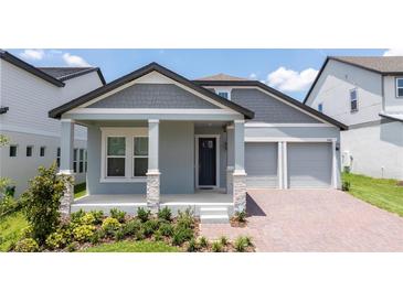 Charming single-Gathering home featuring a light blue exterior, a two-car garage, and a beautifully landscaped front yard at 16489 Silver Brook Way, Winter Garden, FL 34787