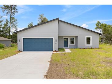 Charming single-story home featuring a modern design, blue garage door, and well-maintained lawn at 2506 Sw 158Th Lane Rd, Ocala, FL 34473