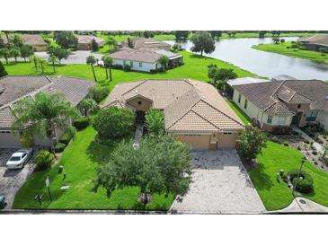Stunning aerial view of a home with a tile roof, lush landscaping, and a serene lake backdrop at 453 Sorrento Rd, Kissimmee, FL 34759