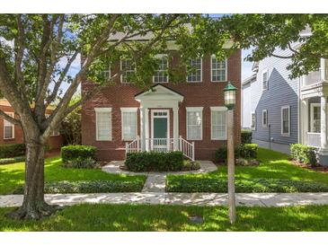 Charming two-story brick home with a well-manicured lawn and lovely green door at 704 Honeysuckle Ave, Kissimmee, FL 34747