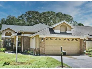 Charming single-story home featuring an attached two-car garage with a well maintained lawn and mature trees at 724 Barrington Cir, Winter Springs, FL 32708
