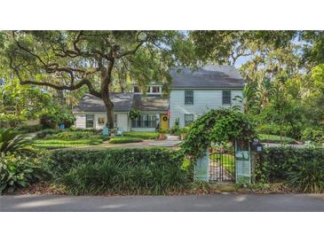 Charming two-story home with mature trees, lush landscaping, and a welcoming yellow front door at 1315 E 24Th St, Sanford, FL 32771