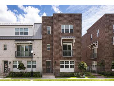 Beautiful brick townhome featuring a landscaped front yard, small balcony, and stylish modern design at 141 S. Park Ave, Winter Garden, FL 34787