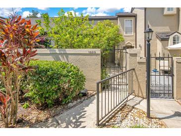 Inviting front entrance with stucco wall, mature landscaping, and secure gated access at 1525 Farrindon Cir, Lake Mary, FL 32746