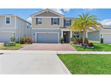 Charming two-story home with a brick driveway, two-car garage and well-manicured lawn, enhanced with a palm tree at 2227 Blue Salvia St, Clermont, FL 34711