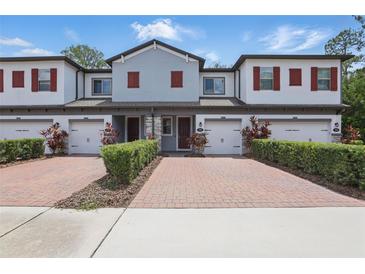 Charming townhome with red shutters, a brick paver driveway, and meticulously maintained landscaping at 328 Cedar Bark Ln, Sanford, FL 32771