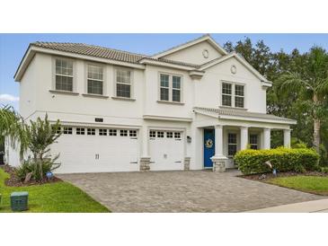 Two-story home featuring a 2 car garage, blue front door, and gray brick driveway at 8811 Bally Neal Loop, Davenport, FL 33896