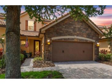Charming home featuring a stone facade, a two-car garage, and a beautifully landscaped front yard at 10430 Belfry Cir, Orlando, FL 32832