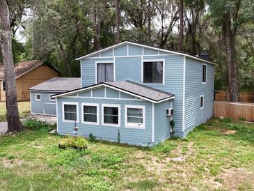 Charming two-story home featuring light blue siding, white trim, and a well-maintained yard surrounded by mature trees at 1288 Se 32Nd St, Ocala, FL 34471
