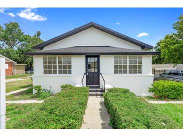 Charming white stucco bungalow featuring black trim, symmetrical windows, and manicured front hedges at 161 Bolender Rd, Auburndale, FL 33823