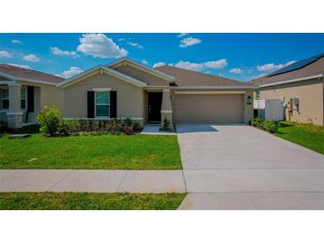 Charming single-Gathering home with a well-maintained lawn, an attached two-car garage, and manicured landscaping at 214 Brave Rd, Davenport, FL 33837