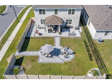 Aerial view of a well-maintained backyard with a patio, fire pit, lush lawn and vinyl fence at 3077 Nottel Dr, St Cloud, FL 34772