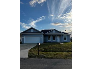 Inviting single-story home featuring a two-car garage, green lawn, and neutral-tone exterior under a blue sky at 567 Viceroy Ct, Kissimmee, FL 34758