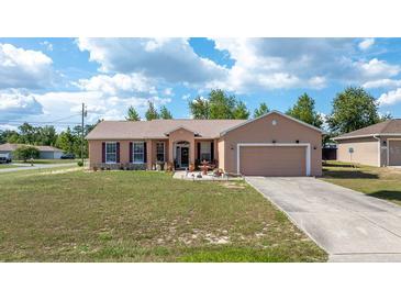 Charming single-story home with a well-maintained lawn, mature trees, and a two-car garage on a sunny day at 7135 Sw 129Th St, Ocala, FL 34473