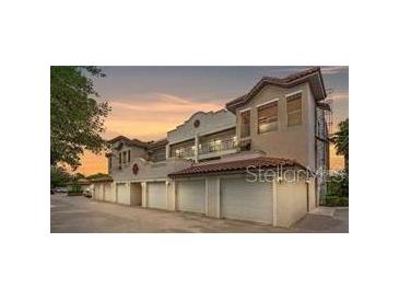 View of a multi-story home with an attached garage featuring a red tile roof and stucco walls at 7842 Holiday Isle Dr # 102, Belle Isle, FL 32812