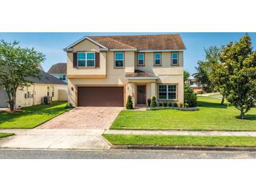 Charming two-story home with a well-manicured lawn and a brick driveway leading to an attached two-car garage at 15058 Sawgrass Bluff Dr, Winter Garden, FL 34787