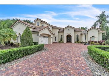 Elegant home with a large brick driveway, manicured landscaping, and a three-car garage at 9729 Lake Hugh Dr, Gotha, FL 34734