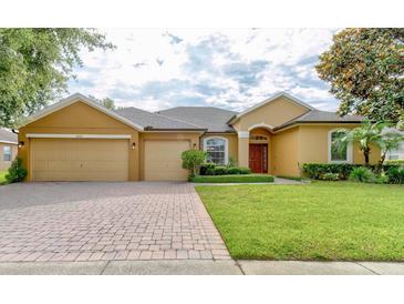 Charming single-Gathering home featuring a manicured front yard, brick driveway, and a spacious three-car garage at 1862 Lorenzo Ln, Oviedo, FL 32765