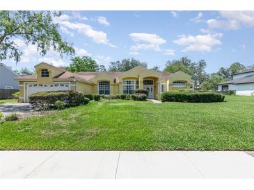 Inviting one-story home with lush front lawn, charming landscaping, and attached two car garage at 1910 Palm View Dr, Apopka, FL 32712