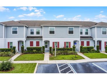 Charming townhome exterior with landscaped front yard and red shutters at 228 Primrose Dr, Davenport, FL 33837