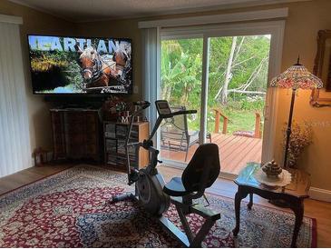 Cozy room with an exercise bike, TV, and sliding glass door to the outdoor deck at 2808 Manatee Rd, Tavares, FL 32778