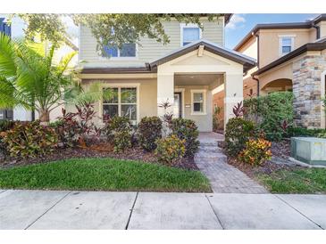 Charming two-story home with well-maintained landscaping, including a palm tree and colorful bushes at 7184 Enchanted Lake Dr, Winter Garden, FL 34787