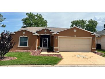 Charming single-story home with manicured lawn, rock landscaping and an attached two car garage at 721 Old Oaks Ln, Leesburg, FL 34748