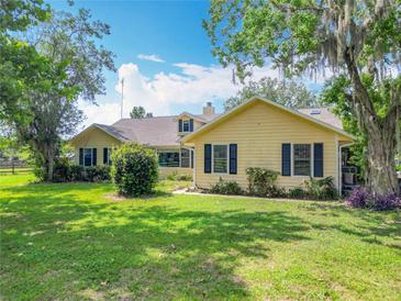 Charming yellow home with black shutters and lush landscaping at 750 Sw 91St Pl, Ocala, FL 34476