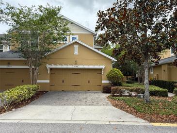 Charming townhome features a tan exterior, a two-car garage, and lovely landscaping at 14344 Desert Haven St, Windermere, FL 34786