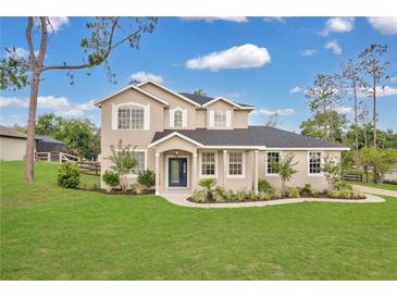 Beautifully landscaped two-story home with a blue front door and lush green lawn at 17657 Windy Pine St, Montverde, FL 34756