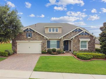 Charming stone facade home with a well-manicured lawn and a two-car garage at 4133 Foxhound Dr, Clermont, FL 34711