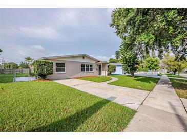 A charming single-story home boasts a well-manicured lawn, a paved driveway, and lush landscaping at 4200 Colony Way, Orlando, FL 32808