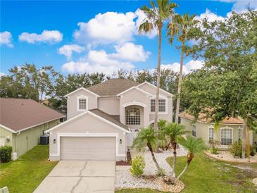 Beautiful two-story home with a well-manicured lawn and tall palm trees at 4993 Hook Hollow Cir, Orlando, FL 32837