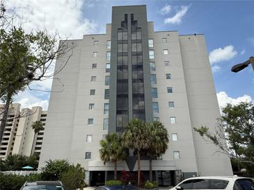 Modern condominium building featuring an elegant entrance and large windows, surrounded by lush landscaping at 6165 Carrier Dr # 1801, Orlando, FL 32819