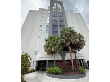 Modern building with palm trees and manicured landscaping offering a luxurious and inviting curb appeal at 6165 Carrier Dr # 1801, Orlando, FL 32819