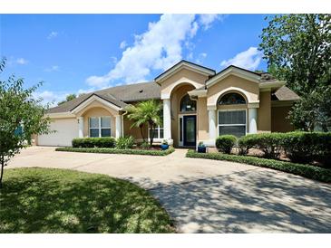 Lovely single-story home featuring a beautiful front lawn, arched entryway, and well-manicured landscaping at 787 High Grove Park Ct, Oviedo, FL 32765