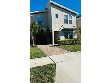 Modern two-story home featuring a stone-accented garage and manicured landscaping at 851 Drop Shot Dr, Davenport, FL 33896