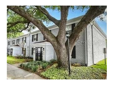 View of the building's exterior with nice landscaping, mature trees, and white painted brick at 141 Lewfield Circle # 141, Winter Park, FL 32792