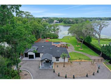 Stunning aerial view of the lakefront home with a pool, cabana, lush landscaping, and a circular driveway at 1700 Lake Markham Rd, Sanford, FL 32771