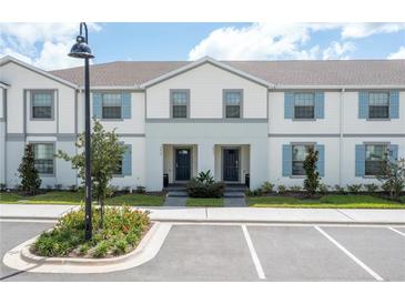 Charming townhome featuring a light exterior, blue shutters and well-maintained landscaping at 2439 Dubai St, Kissimmee, FL 34747
