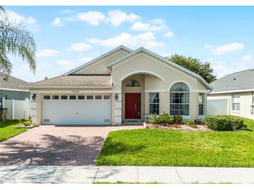 Charming single-story home with a red front door, manicured lawn, and brick paved driveway at 2729 Stanwood Dr, Kissimmee, FL 34743