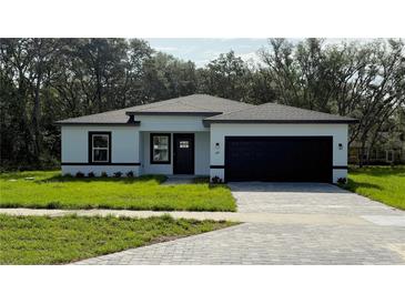 Charming single story home with black trim, a well-manicured lawn, and a paved driveway at 285 Marion Oaks Crse, Ocala, FL 34473