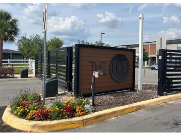 Community entrance sign in front of gated entry, surrounded by colorful flower bed and lush greenery at 3301 Tranquil Trl, Kissimmee, FL 34747