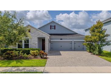 Beautiful two-story home with gray siding, stone accents, and a three-car garage at 4632 Egg Harbor Dr, Kissimmee, FL 34746