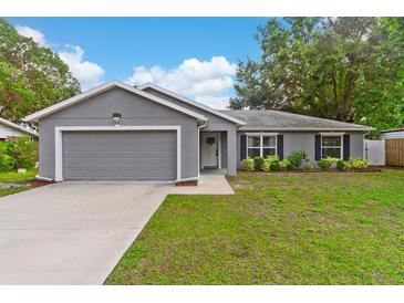 Charming single-story home features a well-manicured lawn, neutral gray paint, and a two-car garage at 122 Seville Rd, Auburndale, FL 33823